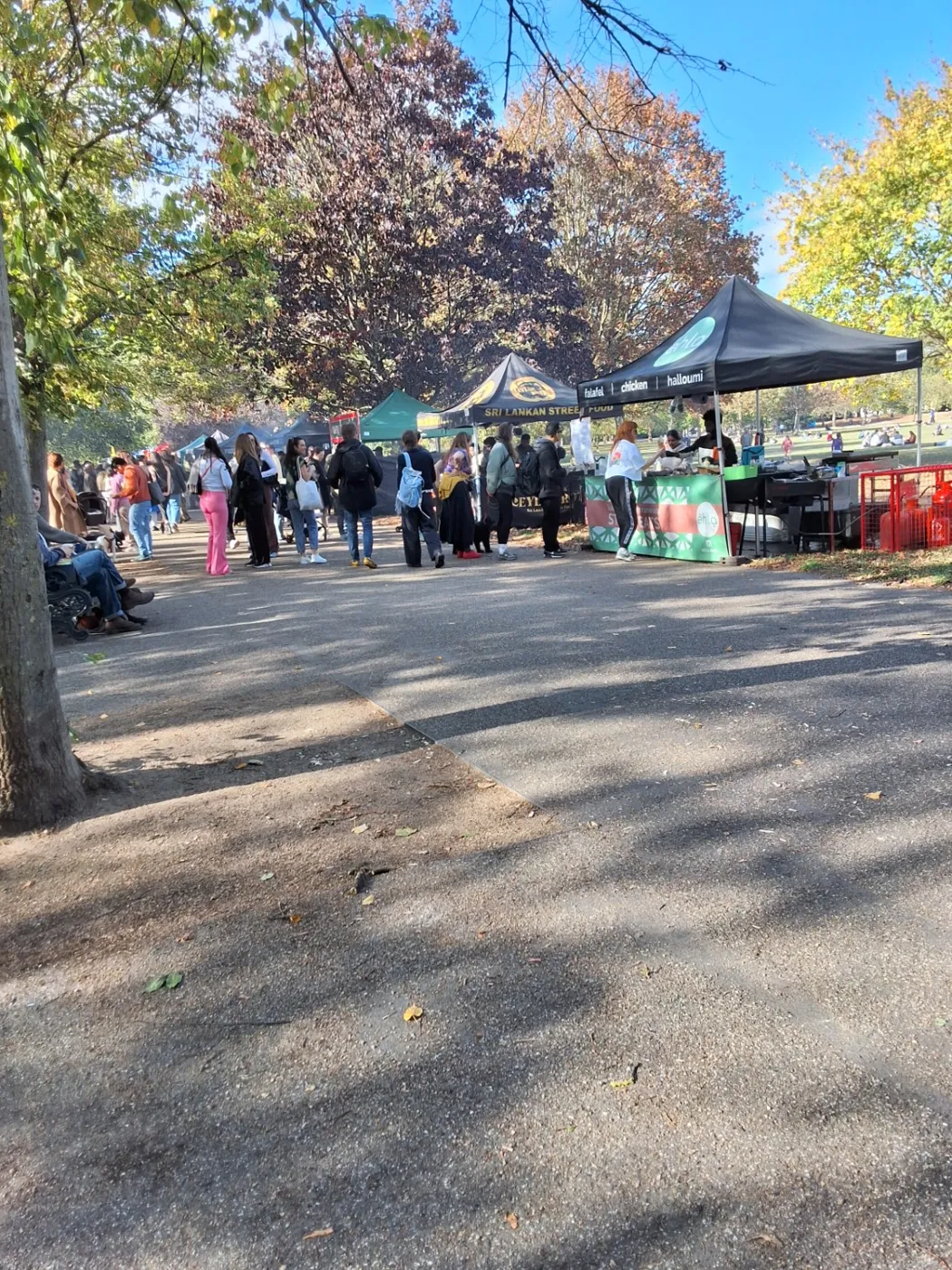Outdoor traders along a tree-lined Victoria Park walkway